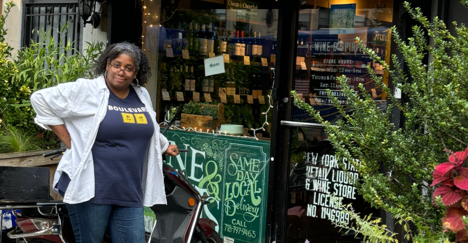 woman leaning on a moped outside a wine shop