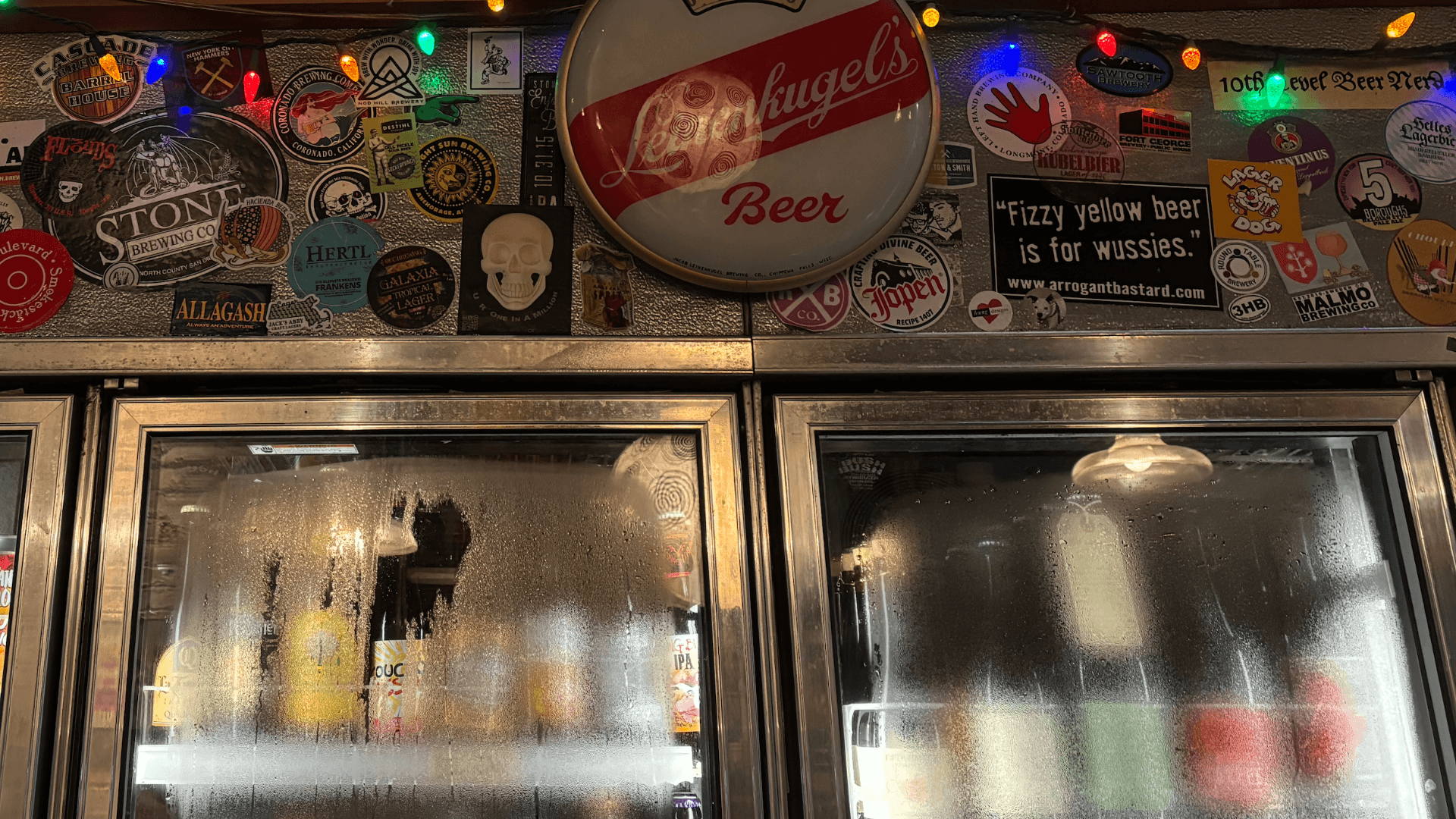 detail of beer fridges covered in stickers and condensation