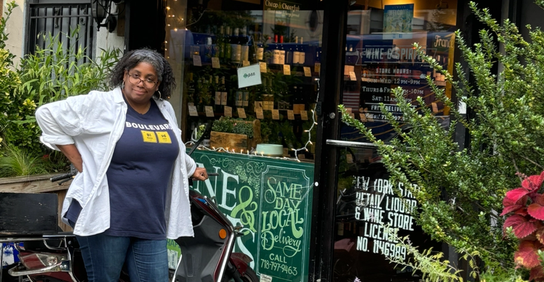 woman leaning on a moped outside a wine shop