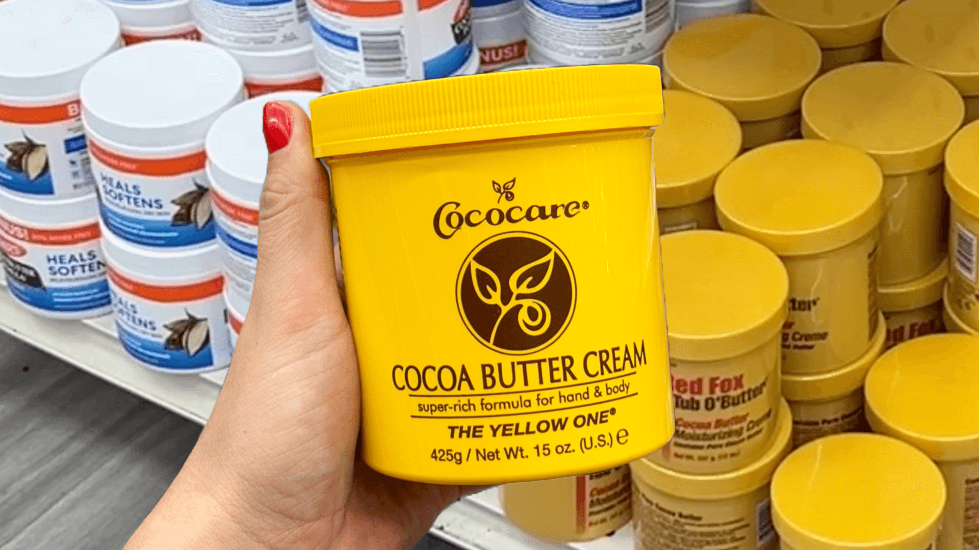 hand holding a yellow tub of cocoa butter cream