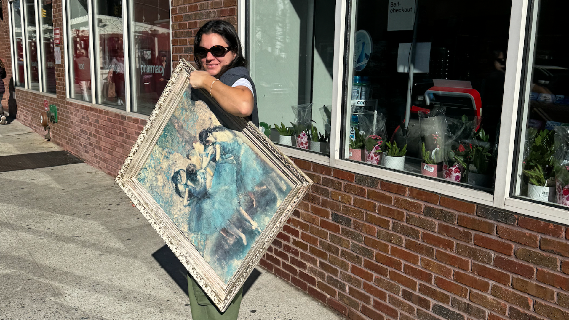person carrying a large framed painting on the sidewalk