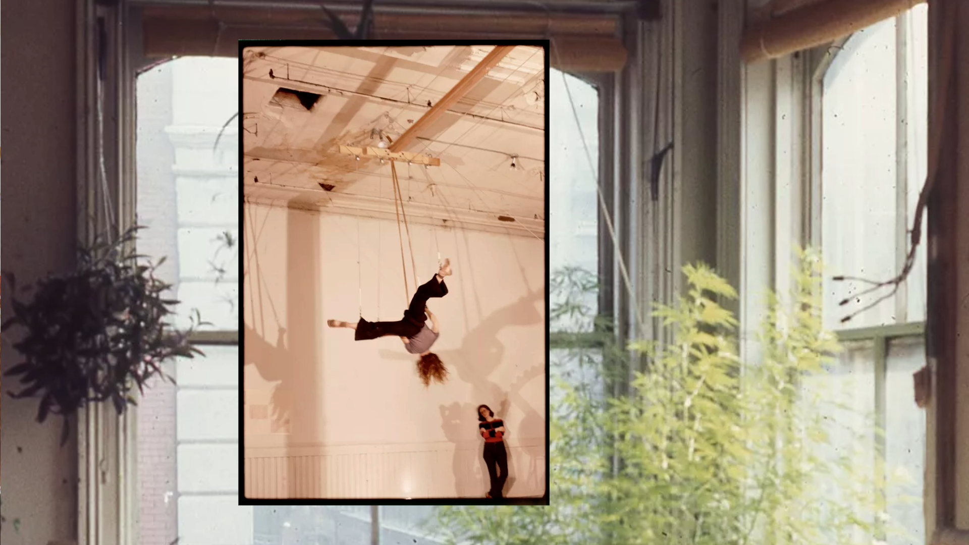 photo of a woman hanging upside down from a loft ceiling on top of photo of a loft interior with books and plants